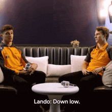 two men are sitting on a couch and one of them is saying " lando down low "