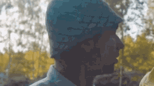 a man wearing a blue hat and a white shirt is standing in front of trees .