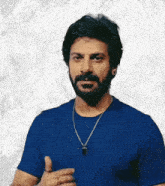 a man with a beard is wearing a blue shirt and a gold necklace