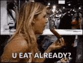 a woman is eating a hot dog with the words `` u eat already '' written on the bottom .
