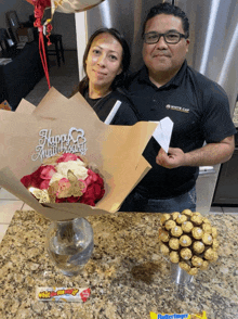 a man in a white cap shirt stands next to a woman holding a happy anniversary sign