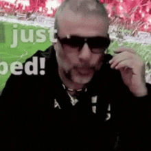 a man wearing sunglasses and a black jacket is talking on a cell phone .