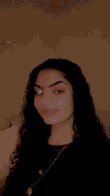 a woman with curly hair and a necklace is smiling