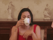 a woman in a red dress is holding a cup of coffee