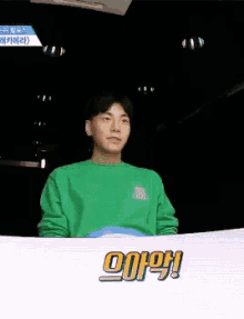 a man in a green shirt is making a funny face with his mouth open