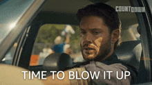 a man is driving a car with the words time to blow it up above him