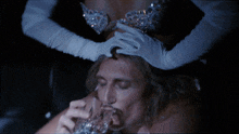 a man drinks from a glass while a woman holds his head