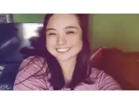a woman in a pink shirt smiles in front of a tv