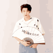 a man is holding a fan that says mistine on it