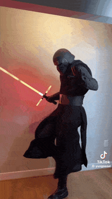 a person dressed as kylo ren from star wars is holding a lightsaber .