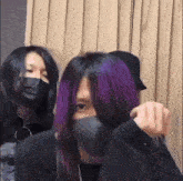 a woman with purple hair is wearing a black mask