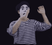 a man dressed as a mime is making a surprised face .