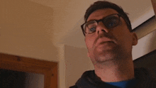 a man wearing glasses and a blue shirt is looking up