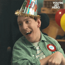 a man in a wheelchair wearing a birthday hat and a badge that says ' you 're my hero ' on it