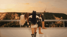 a woman in cowboy boots stands on a balcony overlooking a hollywood sign