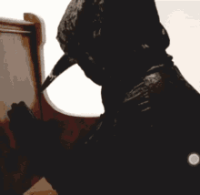 a black dog with a hood on is drinking water