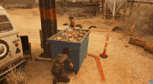 a man is kneeling next to a dumpster that says ' a ' on it