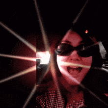 a woman wearing sunglasses and a plaid shirt is surrounded by lights