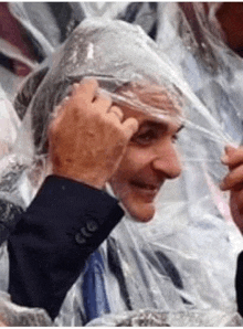 a man in a suit and tie is covering his head with a plastic bag .