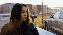 a woman is standing next to a car with a mailbox in the background