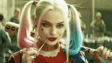 a woman in a harley quinn costume is holding a bat and a cigarette in her mouth .