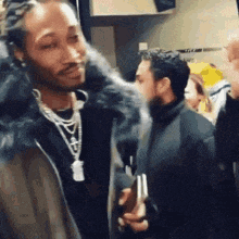 a man in a fur coat is talking to another man in a room .
