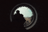 a man is looking out of a round window with the letter t on it