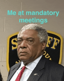 a man in a suit and tie stands in front of a sheriff badge