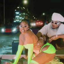 a woman in neon green gloves is being held by a man in sunglasses