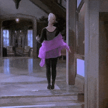 a woman in a black top and purple scarf is walking down stairs