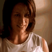 a woman in a white tank top is holding a piece of paper and smiling .