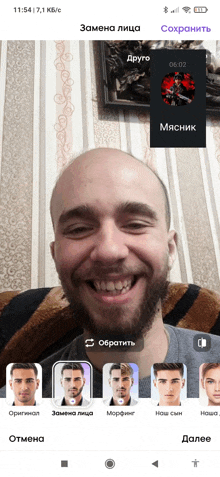 a man with a beard is smiling in front of a screen that says 11:54 on it