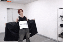 a man in a black tank top is holding a black cloth with yeosan written on it