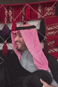 a man wearing a keffiyeh and a robe smiles