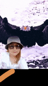 a woman wearing sunglasses and a hat is standing in front of an eagle