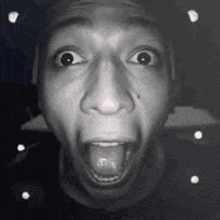 a black and white photo of a man with his mouth open and his tongue out .
