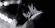 a man and a woman are kissing in a black and white photo . the woman is wearing headphones .