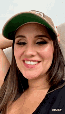 a woman wearing a baseball cap is smiling and rbd.gif is below her