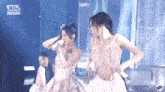 two women in pink dresses are dancing on a stage .