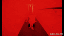 a blurry picture of a person in a red room with the website gifrun.com below them
