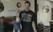 a man in a black shirt is holding a baby in his arms in a blurry photo .