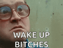 a man wearing glasses is making a face and says `` wake up bitches '' .