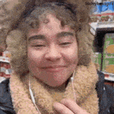a woman wearing ear muffs and headphones is smiling in a grocery store