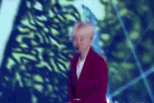 a man in a red suit is standing in front of a blue background .