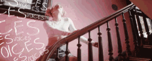 a woman is sitting on a set of stairs with the words " voices " written on the wall behind her