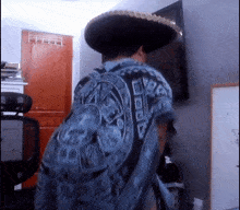 a man wearing a sombrero and a blue shirt with a skull on it