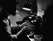 a man smoking a cigarette and typing on a typewriter