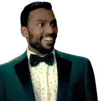 a man in a tuxedo and bow tie smiles for the camera