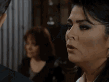 a close up of a woman 's face with another woman in the background .