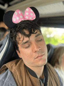 a man wearing minnie mouse ears is sleeping